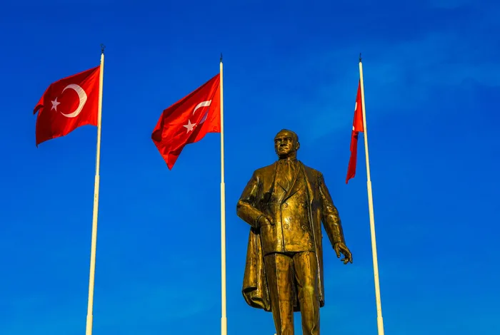 Türk bayrakları önünde bronz Atatürk heykeli