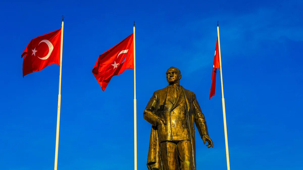 Türk bayrakları önünde bronz Atatürk heykeli